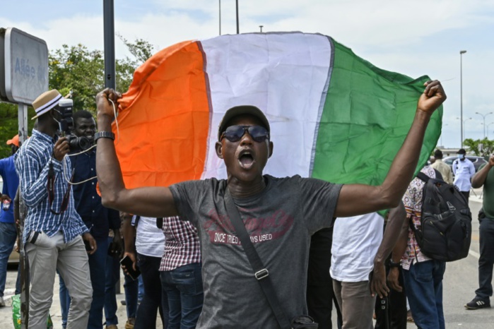 Un homme déploie le drapeau ivoirien pour le retour au pays de partisans de l'ex-président Laurent Gbagbo après dix ans d'exil, le 30 avril 2021 à Abidjan.  Crédit Photo : SIA KAMBOU